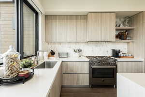 Kitchen with light wood finish cabinetry, high end stainless steel range oven, and modern cabinets