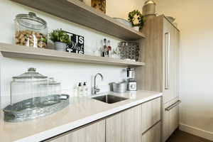 Bar area featuring open shelves, light wood finish cabinets, modern cabinets, dark wood-style flooring, and light stone counters