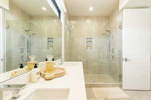 Full bath featuring a shower stall, double vanity, and recessed lighting
