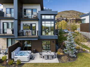 Rear view of house featuring a balcony, a mountain view, a hot tub, a patio area, and outdoor dining space