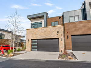 Contemporary townhome with stone siding, concrete driveway, and a garage