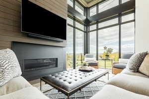 Living room with expansive windows, a fireplace, a high ceiling, wood walls, and wood finished floors