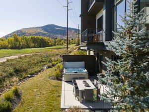 Patio / terrace with a mountain view, a hot tub, a lawn, and a patio area