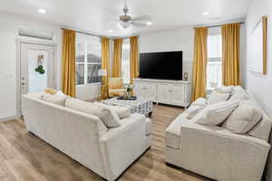 Living room with light wood-type flooring, a ceiling fan, and recessed lighting