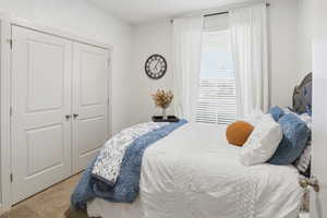 Bedroom with light colored carpet and a closet