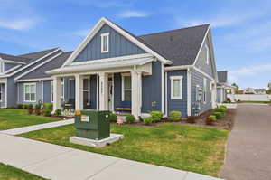View of front of home with board and batten siding, a porch, a front yard, and roof with shingles
