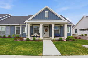 View of front facade with a porch, board and batten siding, and a front lawn