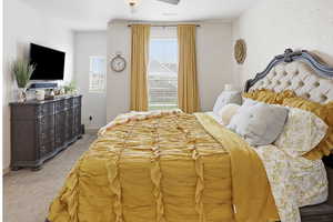 Carpeted bedroom with ceiling fan and baseboards