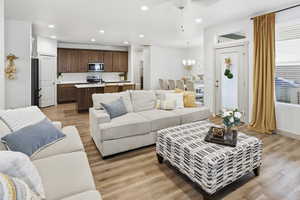 Living area with light wood-style flooring, ceiling fan, and hanging lights