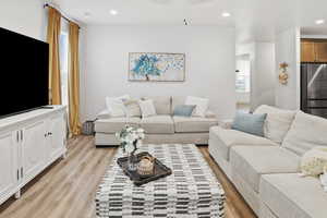 Living room with healthy amount of natural light, light wood-style flooring, wallpapered walls, and recessed lighting