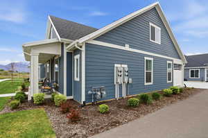 View of home's exterior featuring a mountain view, a yard, covered porch, and roof with shingles