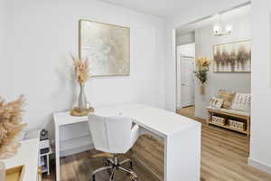 Office area with light wood-style floors and a chandelier