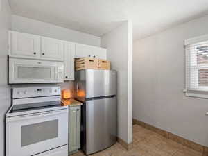 Kitchen featuring white appliances, light stone countertops, and two tone cabinetry