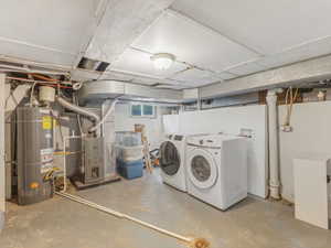 Below grade area with water heater, separate washer and dryer, and heating unit