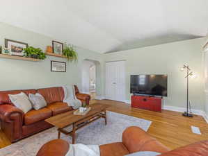 Living area with light wood-type flooring, arched walkways, and vaulted ceiling