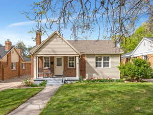 Bungalow-style house with a porch, a front lawn, and brick siding