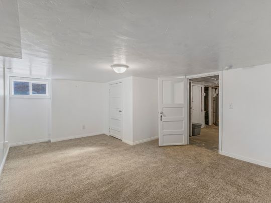 Finished below grade area featuring light colored carpet and baseboards