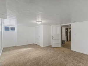 Finished below grade area featuring light colored carpet and baseboards