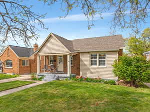 Bungalow-style house featuring a porch, a front lawn, and brick siding