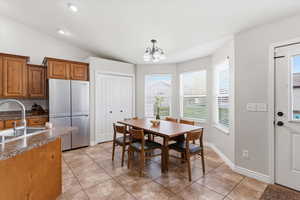 Dining room with light tile patterned flooring, hanging lights, lofted ceiling, and healthy amount of natural light