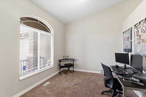 Carpeted home office with lofted ceiling and baseboards