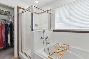 Bathroom with a spacious closet, a shower stall, and a garden tub