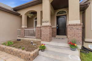 Doorway to property featuring a porch, stucco siding, and brick siding