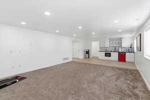 Unfurnished living room with light colored carpet and recessed lighting