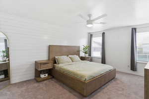 Carpeted bedroom featuring multiple windows and ceiling fan