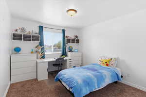 Bedroom with dark colored carpet and an office area