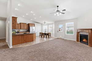 Kitchen featuring wood finish cabinetry, open floor plan, dark stone countertops, light carpet, and a tile fireplace