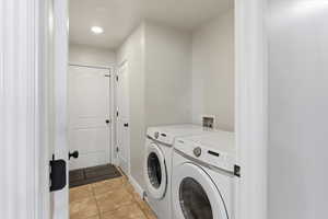 Laundry area featuring light tile patterned floors, washer and dryer, and recessed lighting