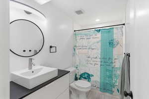 Bathroom with vanity, curtained shower, and recessed lighting