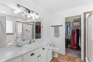 Full bath with a shower stall, a spacious closet, vanity, and light tile patterned floors