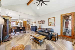 Living room with light wood finished floors, suspended lighting, and ceiling fan