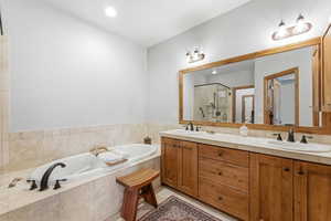 Full bathroom featuring double vanity, a bath, a shower stall, light tile patterned floors, and recessed lighting