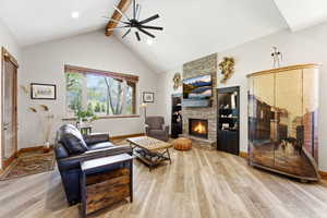 Living room featuring a stone fireplace, light wood finished floors, and a ceiling fan