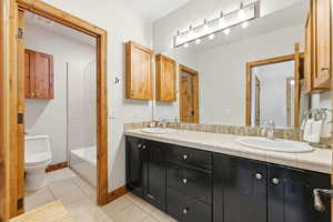 Bathroom with double vanity, light tile patterned floors, and shower / washtub combination