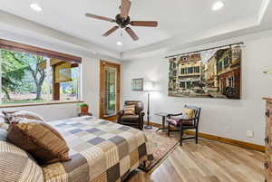 Bedroom with wood finished floors, recessed lighting, access to exterior, a ceiling fan, and a raised ceiling