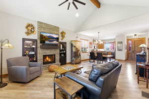 Living area featuring ceiling fan, light wood-type flooring, a fireplace, and hanging lights