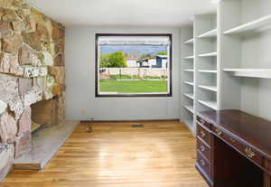 Bedroom or Office Unfurnished living room with a textured ceiling, light wood-type flooring, and a stone fireplace