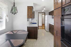 Kitchen featuring light countertops, freestanding refrigerator, brick patterned floors, dark wood finish cabinetry, and pendant lighting