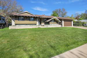 View of front of home with a garage, a front lawn, board and batten siding, and driveway