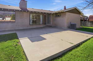 Back of house featuring a chimney, a patio area, and brick siding