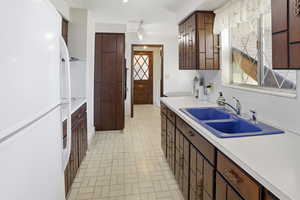 Kitchen featuring freestanding refrigerator, dark wood finish cabinetry, and light countertops