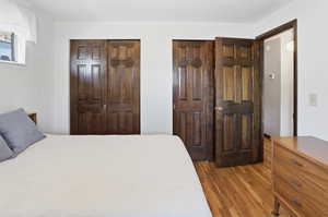 Bedroom featuring multiple closets, a textured ceiling, and wood finished floors