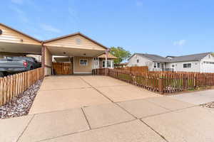 Ranch-style house featuring a fenced front yard, an attached carport, and concrete driveway