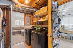 Laundry area featuring electric panel, light colored carpet, washer and clothes dryer, and a ceiling fan