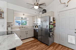 Kitchen featuring a ceiling fan, light wood-style floors, stainless steel appliances, and white cabinets