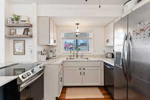 Kitchen featuring stainless steel appliances, white cabinetry, dark wood-type flooring, and open shelves